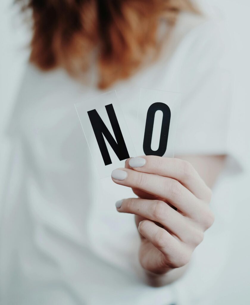 woman holding the words "no" in her hand. - trying to stop people pleasing.