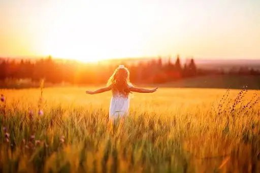 A carefree little girl running in a sunny meadow, symbolizing the emotional liberation and pure joy restored to the psyche via IFS parts work.